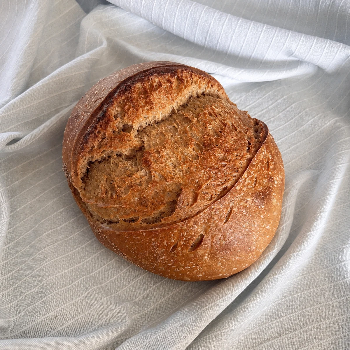 Rond boerenbrood zuurdesem met open insnede, op linnen